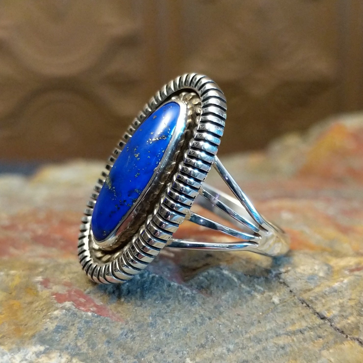 Sterling silver ring with oval lapis set in the bezel, framed by twisted rope and incised edges.
