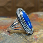 Sterling silver ring with oval lapis set in the bezel, framed by twisted rope and incised edges.