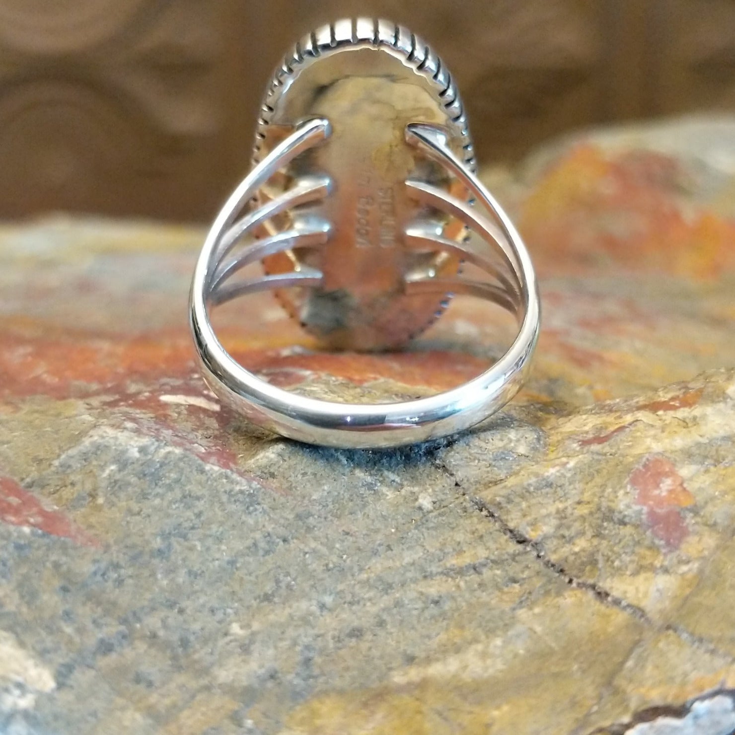 Sterling silver ring with oval lapis set in the bezel, framed by twisted rope and incised edges.