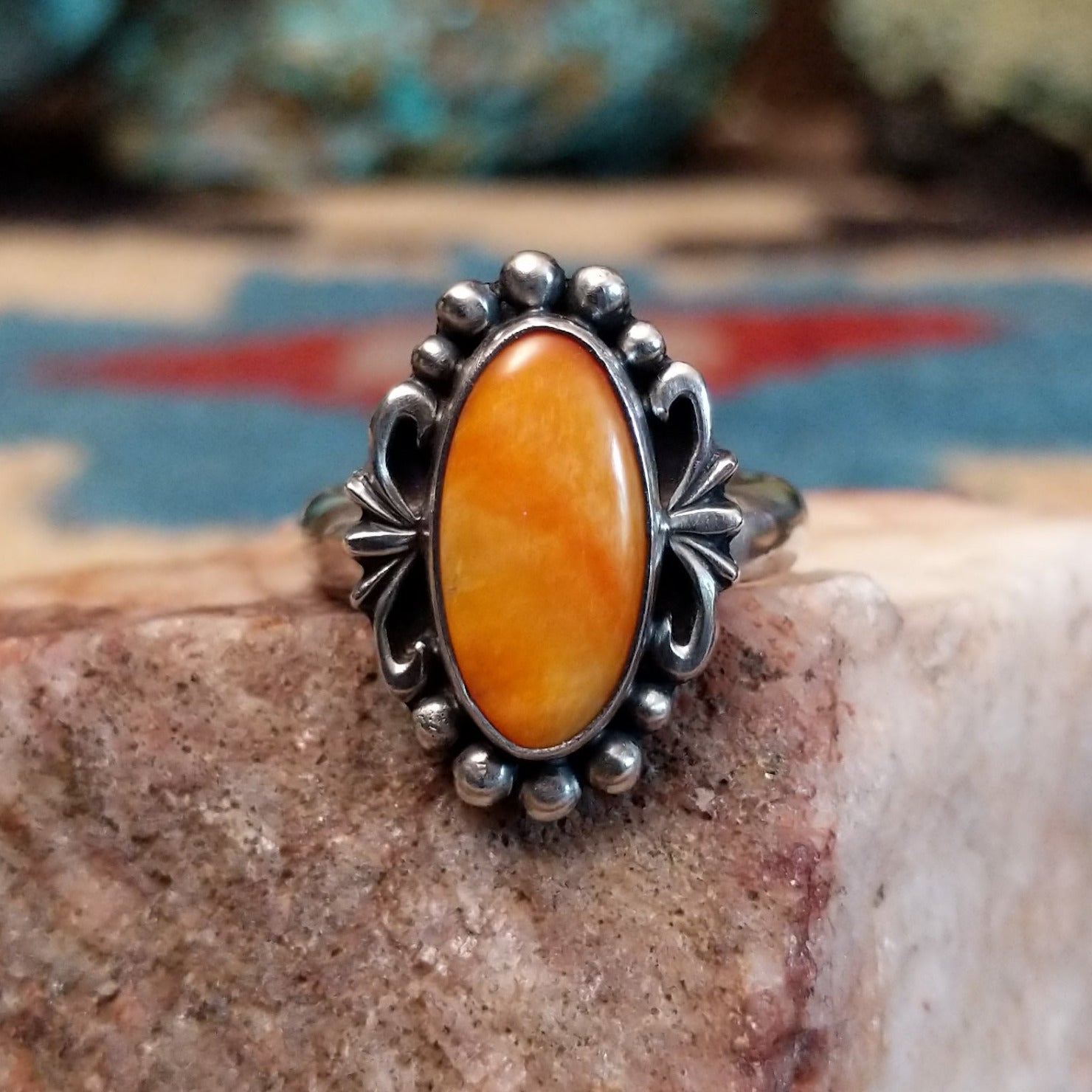 Sterling silver ring with orange oyster shell in an oval bezel.