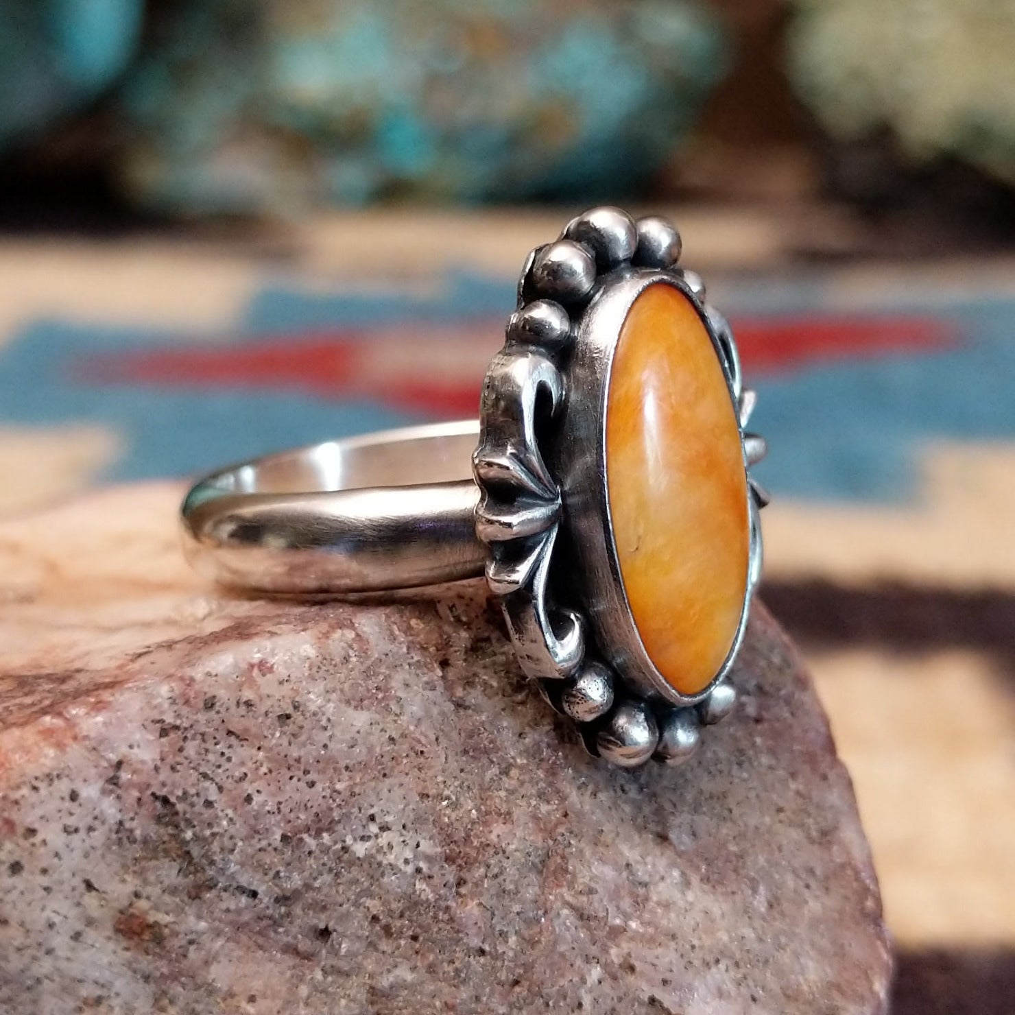 Sterling silver ring with orange oyster shell in an oval bezel.