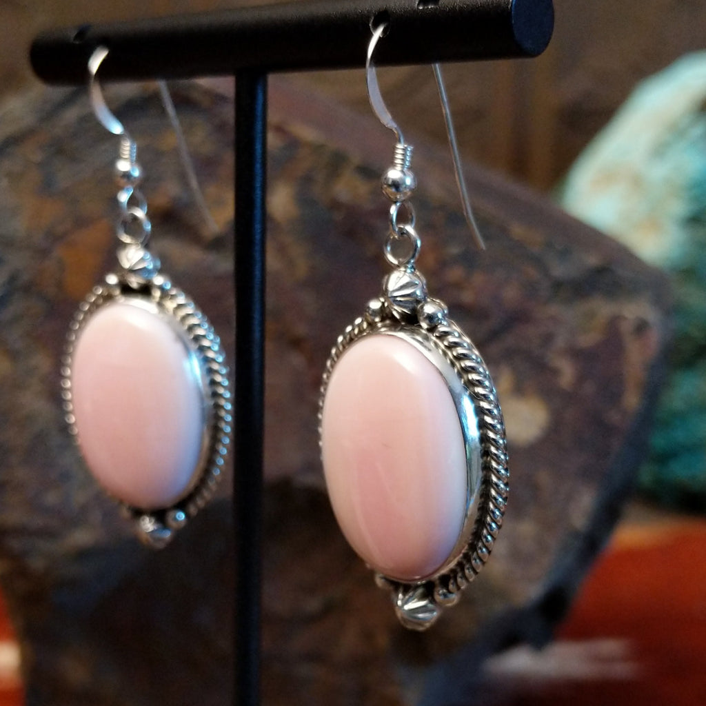 Sterling silver earrings with pink conch shell earrings set within twisted rope and dotted accent bezels.