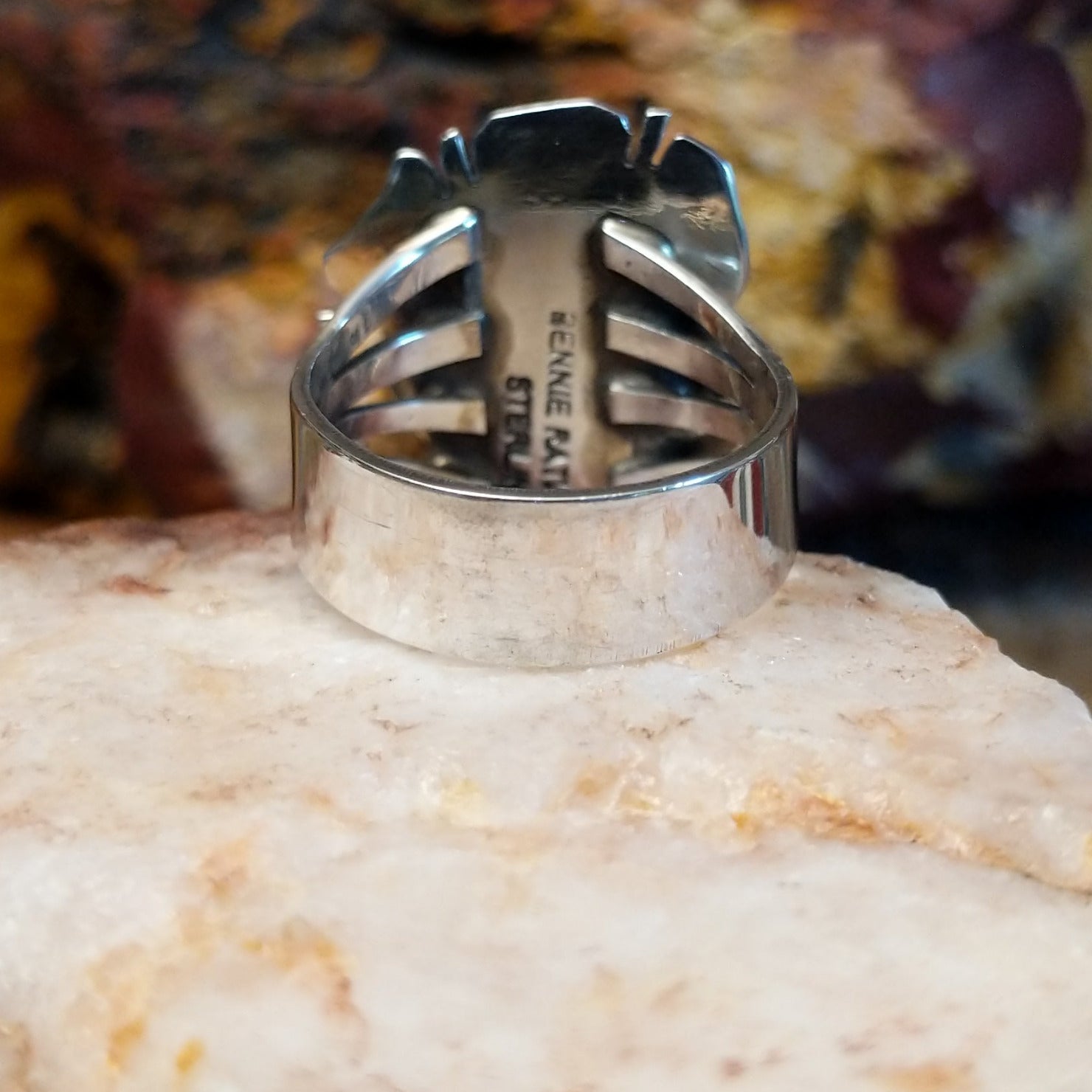 Square sugilite ring set within an intricate silver work bezel.