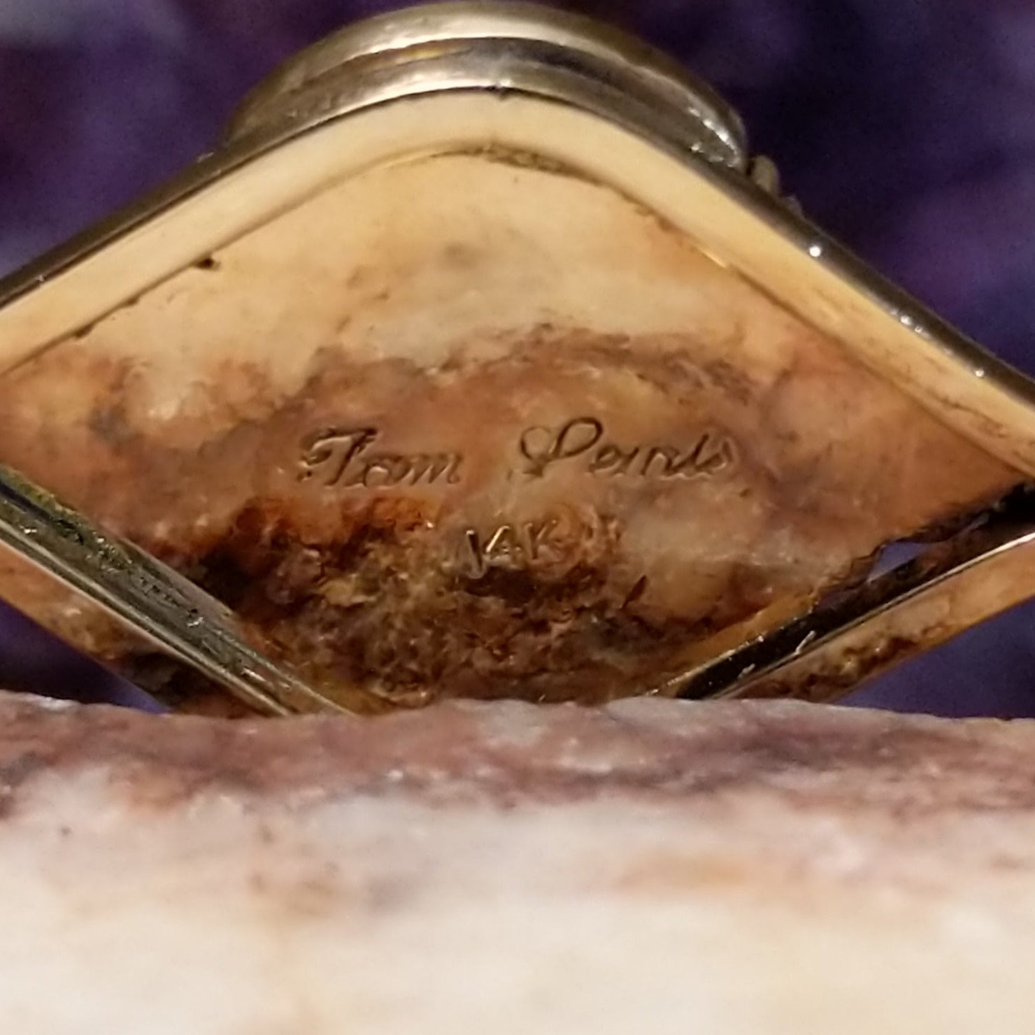 Close up of artist's stamped signature and stamped 14K, indicating 14 karat gold construction.