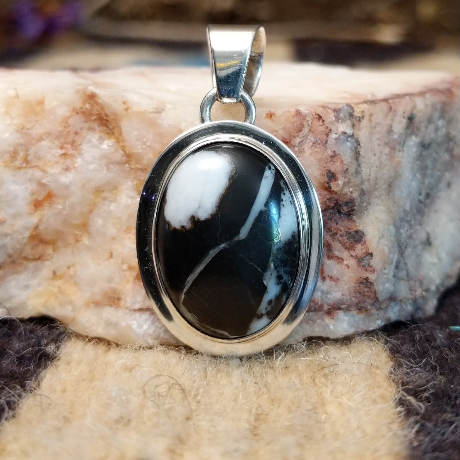 Sterling silver pendant with white buffalo stone set in an oval bezel, framed by the silverwork ledge.