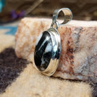Sterling silver pendant with white buffalo stone set in an oval bezel, framed by the silverwork ledge.