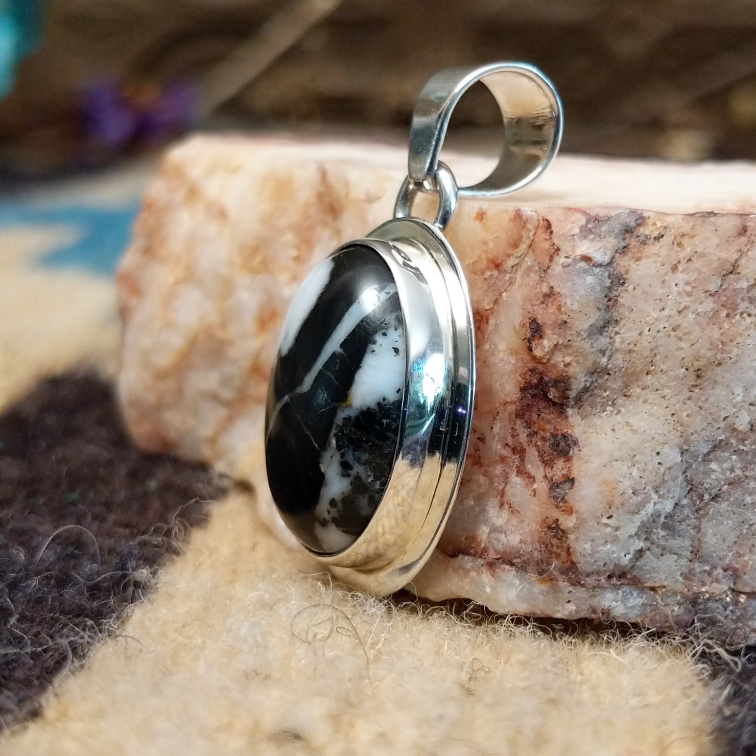 Sterling silver pendant with white buffalo stone set in an oval bezel, framed by the silverwork ledge.