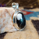 Sterling silver pendant with white buffalo stone set in an oval bezel, framed by the silverwork ledge.