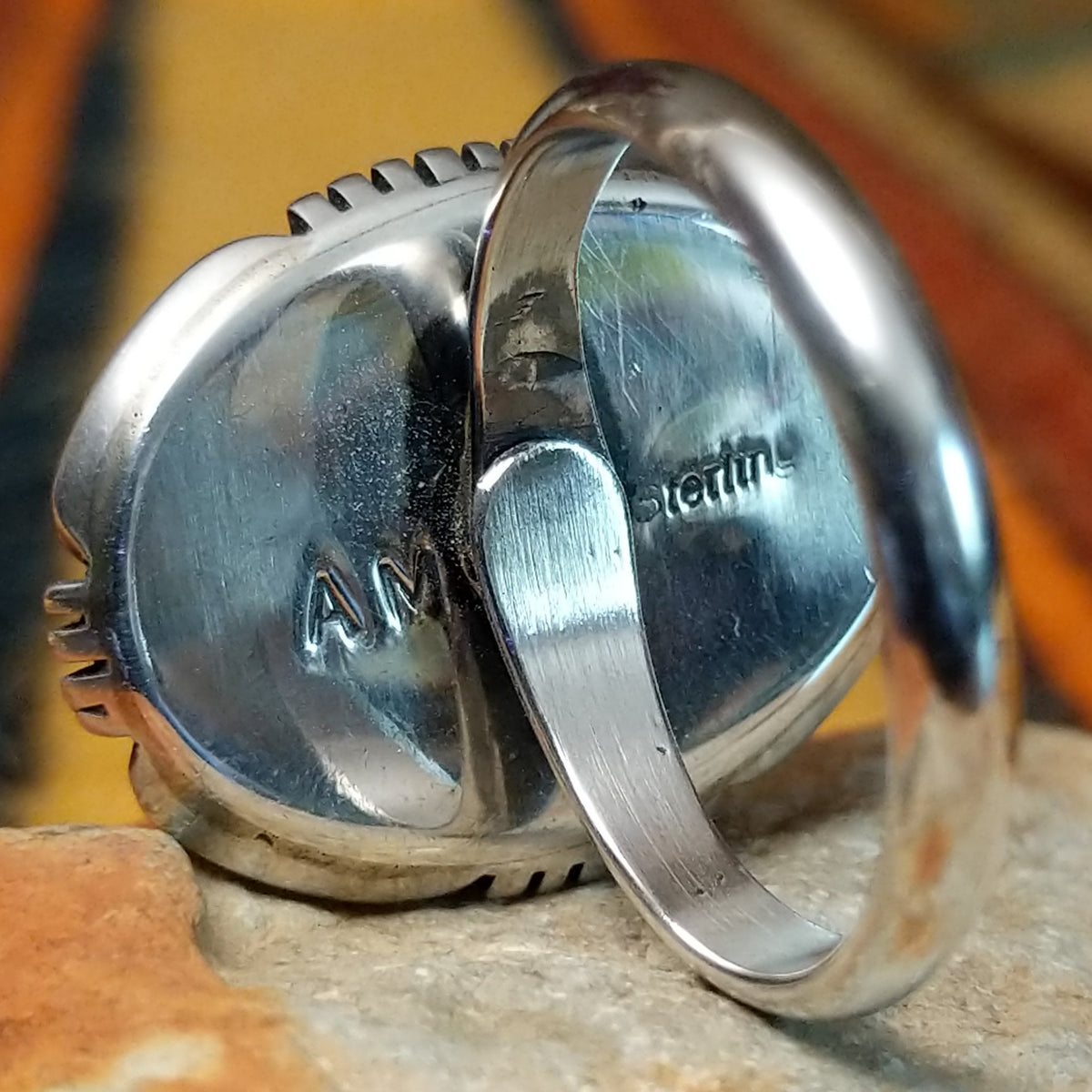 This distinctive White Buffalo Ring by Alfred Martinez features a large oval white stone with black matrix patterns, surrounded by a silver rope border and decorative stamped silver setting; artisan and Sterling Silver stamp.