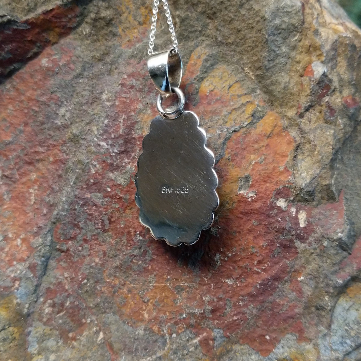 Turquoise pendant by Burt Francisco featuring a large teardrop-shaped blue turquoise stone surrounded by twisted rope and scalloped sterling silverwork; artisan and .925 (Sterling Silver) stamp.