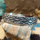 Sterling silver cuff bracelet with stamped designs on the surface.