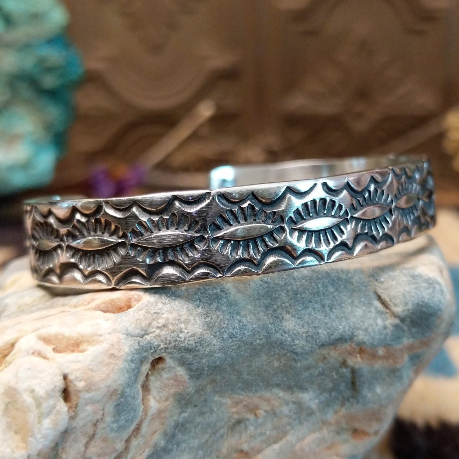 Sterling silver cuff bracelet with stamped designs on the surface.