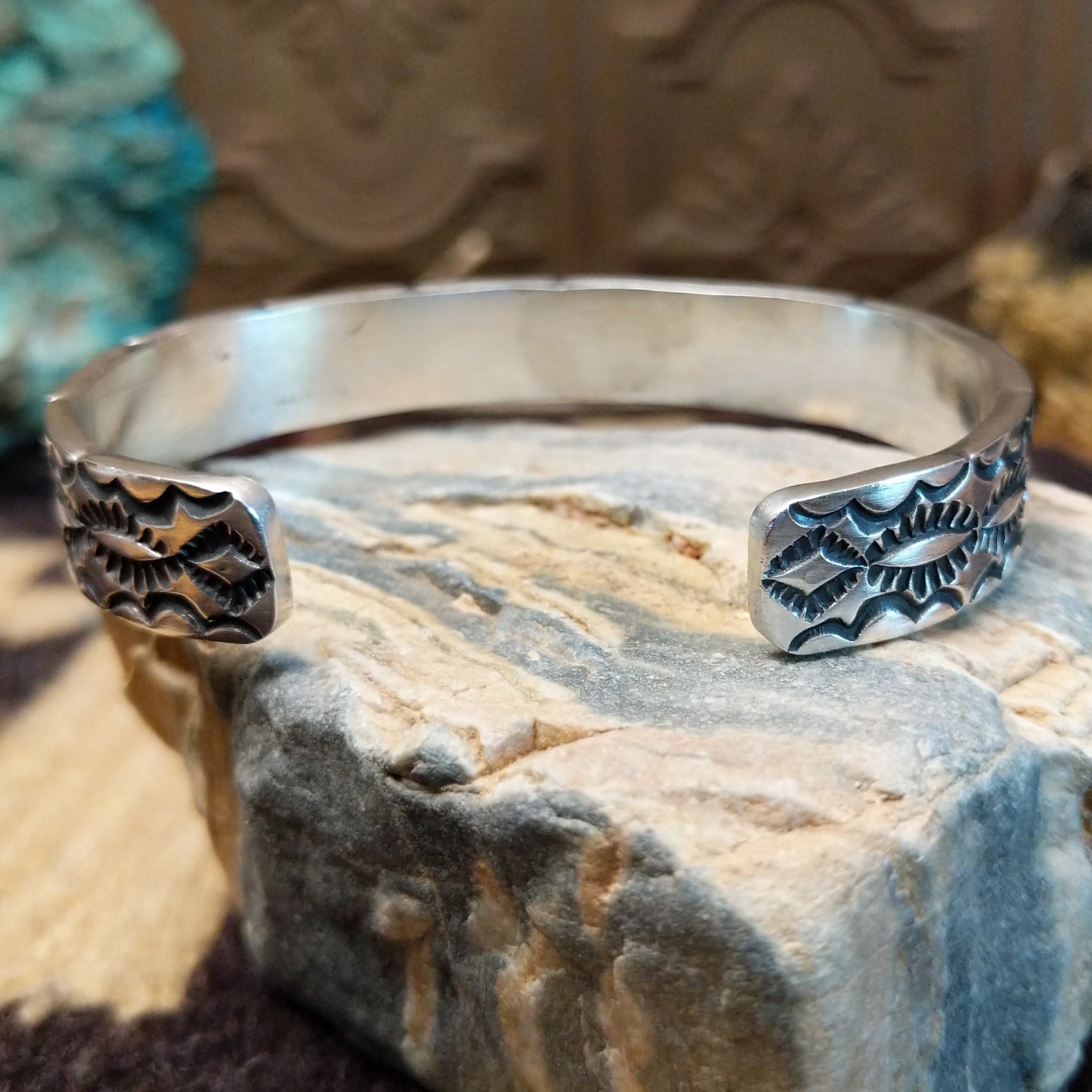 Sterling silver cuff bracelet with stamped designs on the surface.