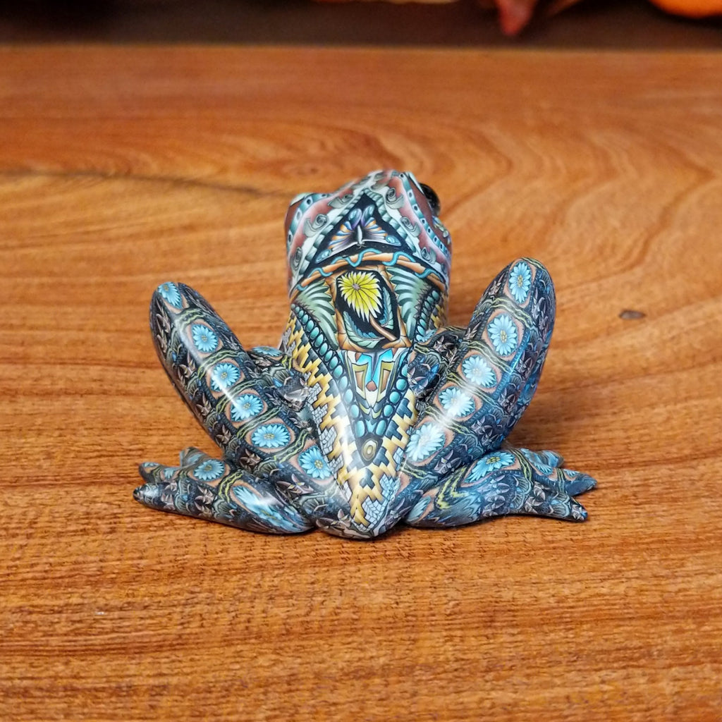 Polymer clay shaped into a frog with intricate designs and vibrant colors on the body.