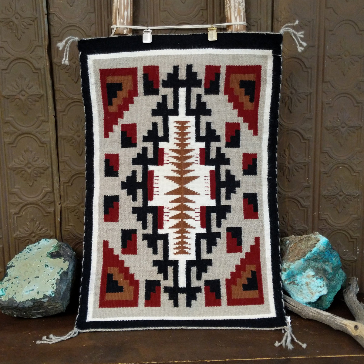A splendid Navajo rug handmade by artist Laberta Yazzie with wools dyed an assortment of exquisite colors. The rich red holds beauty throughout the many interesting designs. A striking piece of art for home decor!