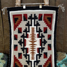 A splendid Navajo rug handmade by artist Laberta Yazzie with wools dyed an assortment of exquisite colors. The rich red holds beauty throughout the many interesting designs. A striking piece of art for home decor!