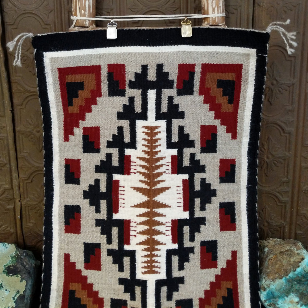 A splendid Navajo rug handmade by artist Laberta Yazzie with wools dyed an assortment of exquisite colors. The rich red holds beauty throughout the many interesting designs. A striking piece of art for home decor!