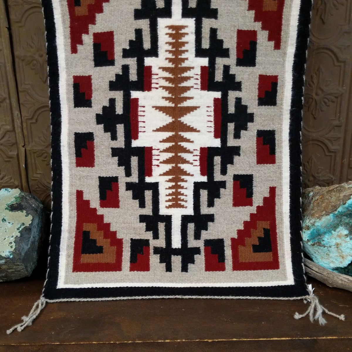 A splendid Navajo rug handmade by artist Laberta Yazzie with wools dyed an assortment of exquisite colors. The rich red holds beauty throughout the many interesting designs. A striking piece of art for home decor!