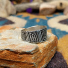 Sterling silver geometric band ring by Elgin Tom with hand-stamped spiral patterns; side view.