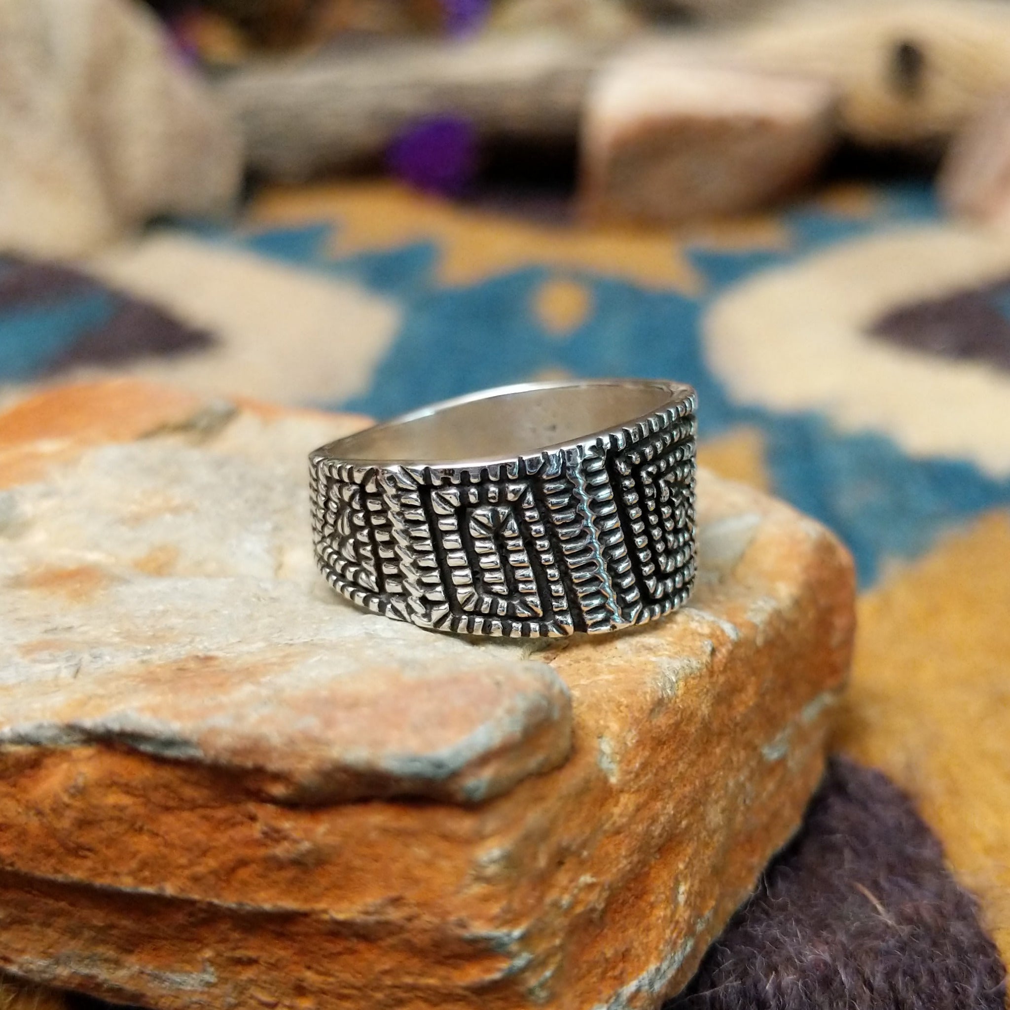Sterling silver geometric band ring by Elgin Tom with hand-stamped spiral patterns; side view.