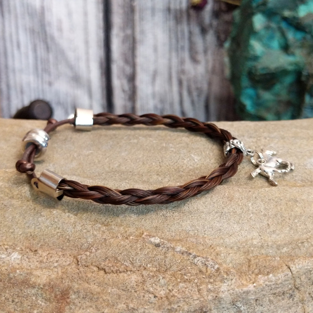 Braided brown horsehair bracelet with a adjustable cord and a metal horse charm.