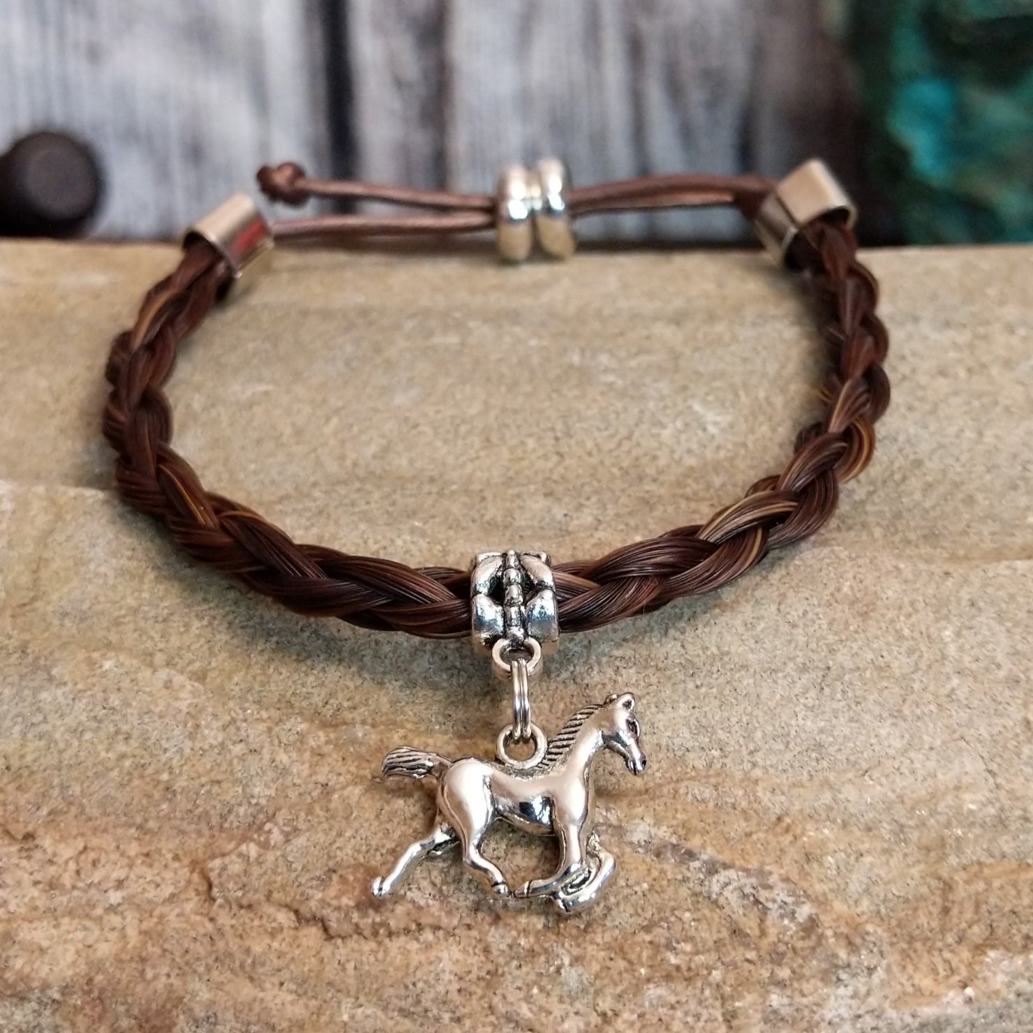 Braided brown horsehair bracelet with a adjustable cord and a metal horse charm.