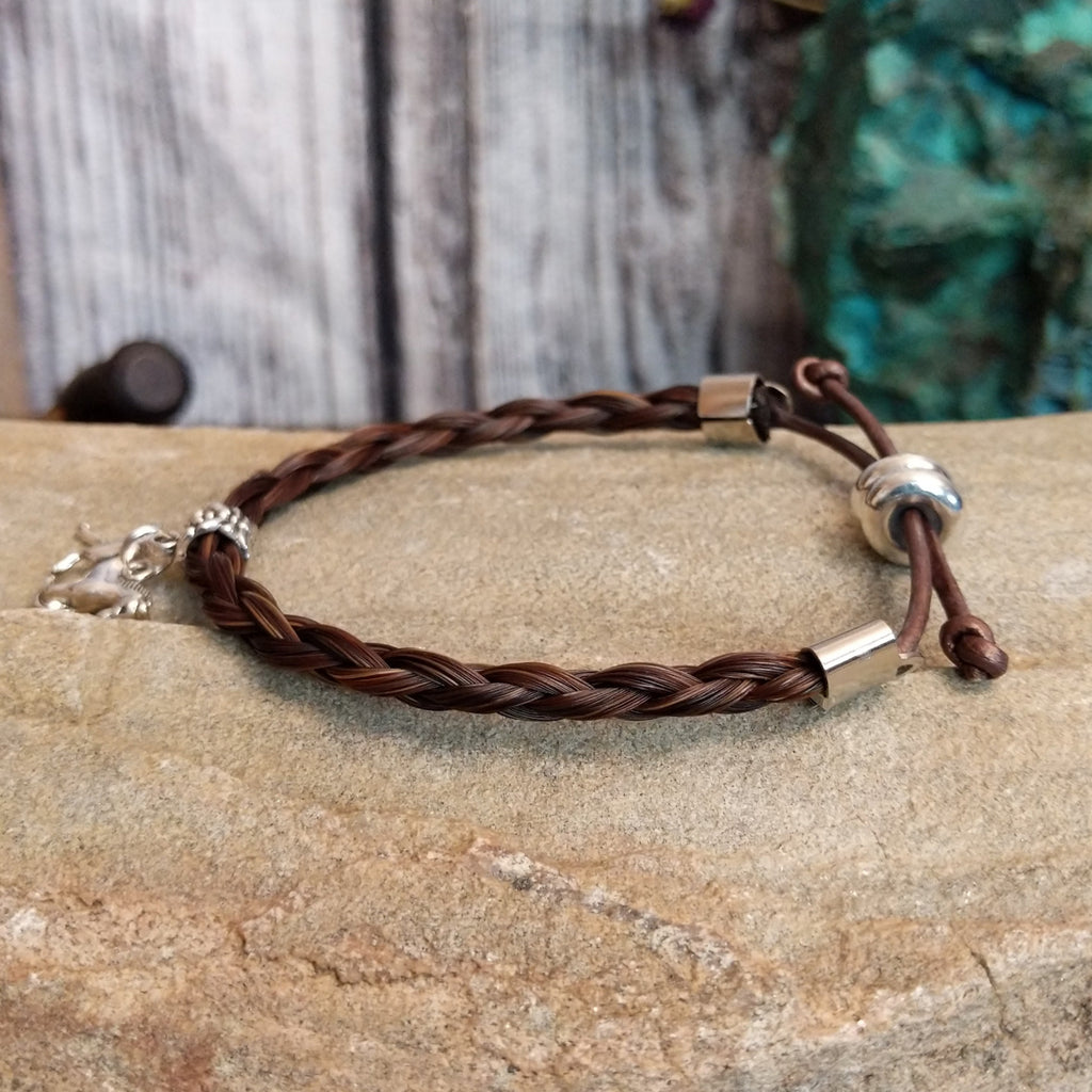 Braided brown horsehair bracelet with a adjustable cord and a metal horse charm.