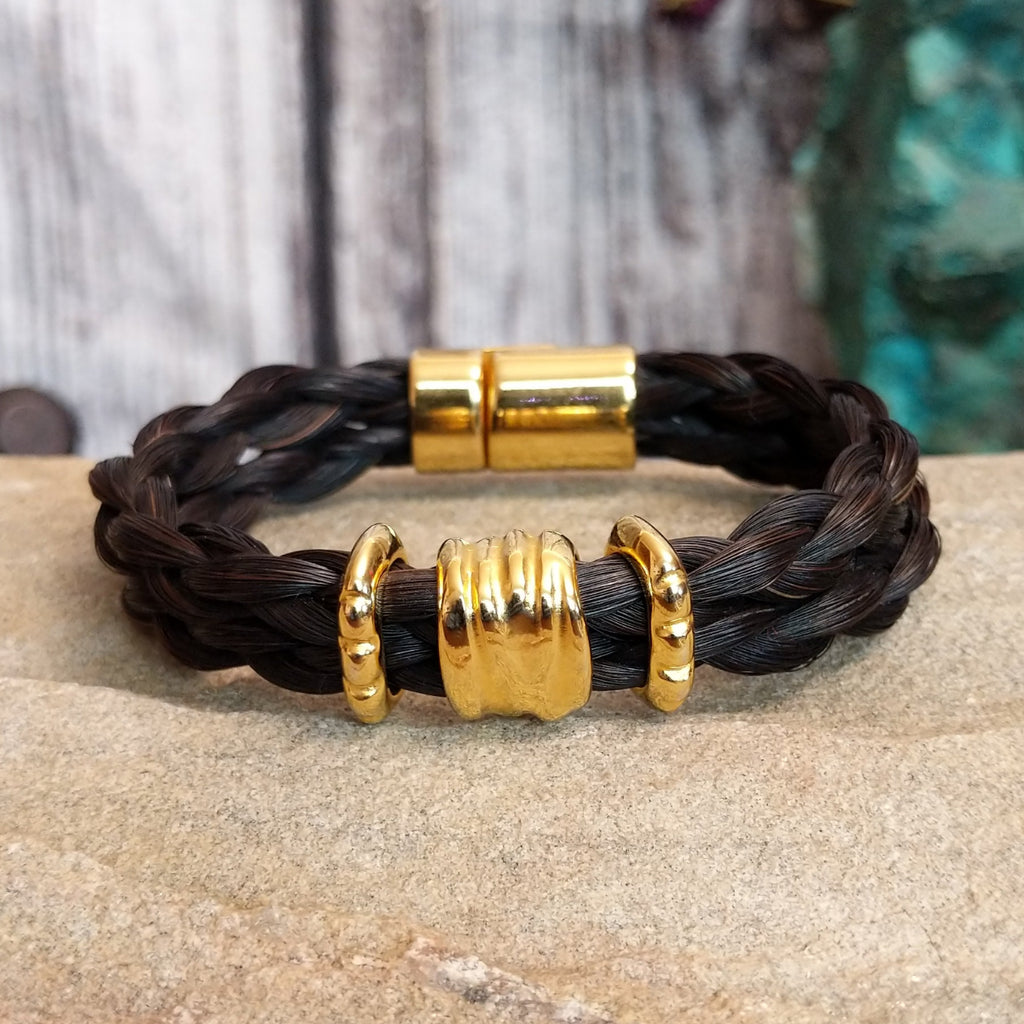 A braided dark brown horsehair bracelet with gold-toned accents and a magnetic clasp.