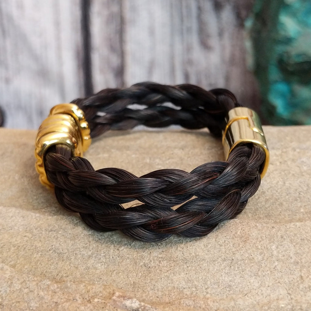 A braided dark brown horsehair bracelet with gold-toned accents and a magnetic clasp.