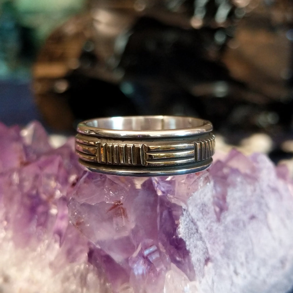 A sterling silver band with gold inlay in a geometric design.