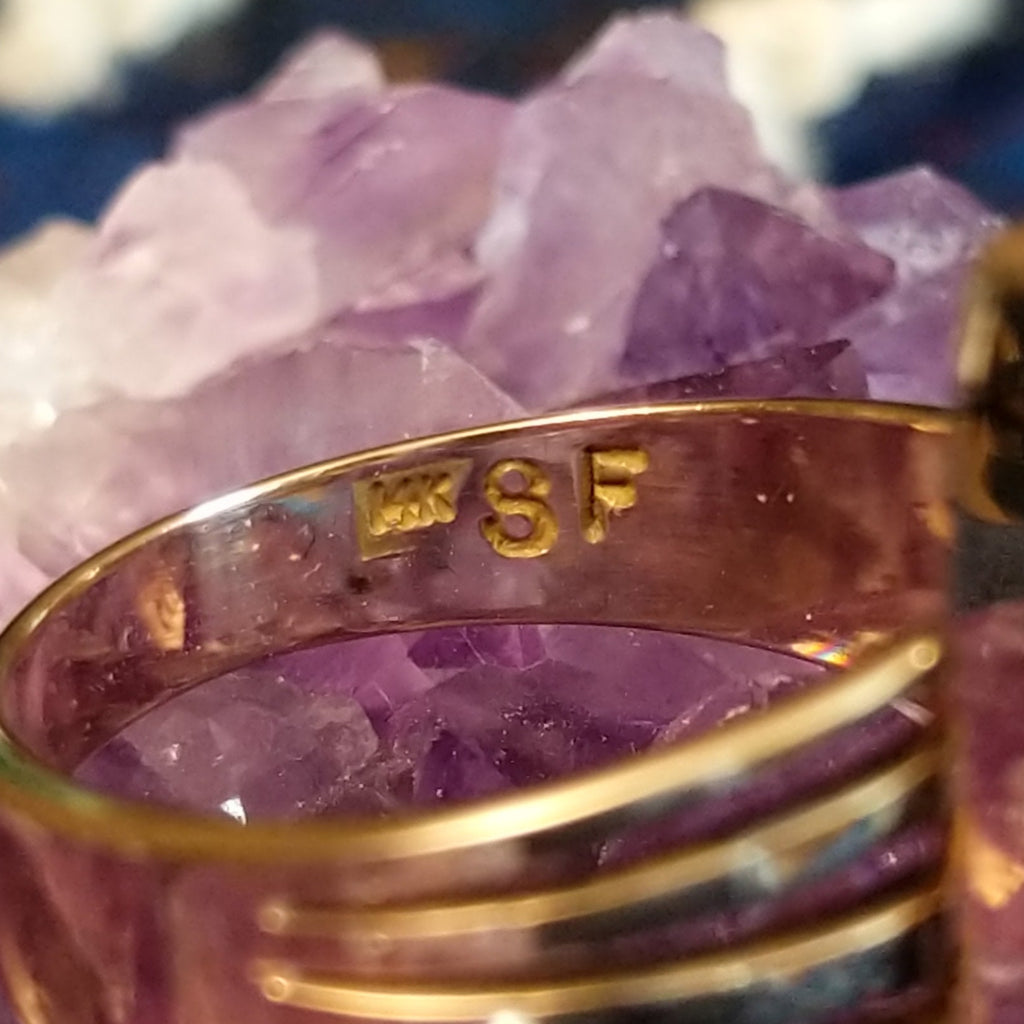 The artist's initials are etched into the band of the ring.