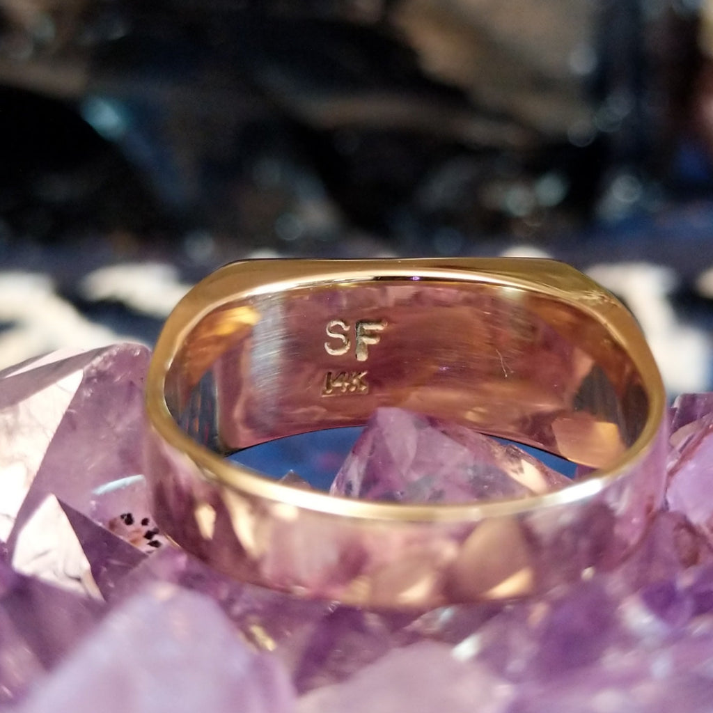 The etched signature of the artist is in the inside of the ring.