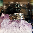A sleek gold and silver ring featuring intricate designs.
