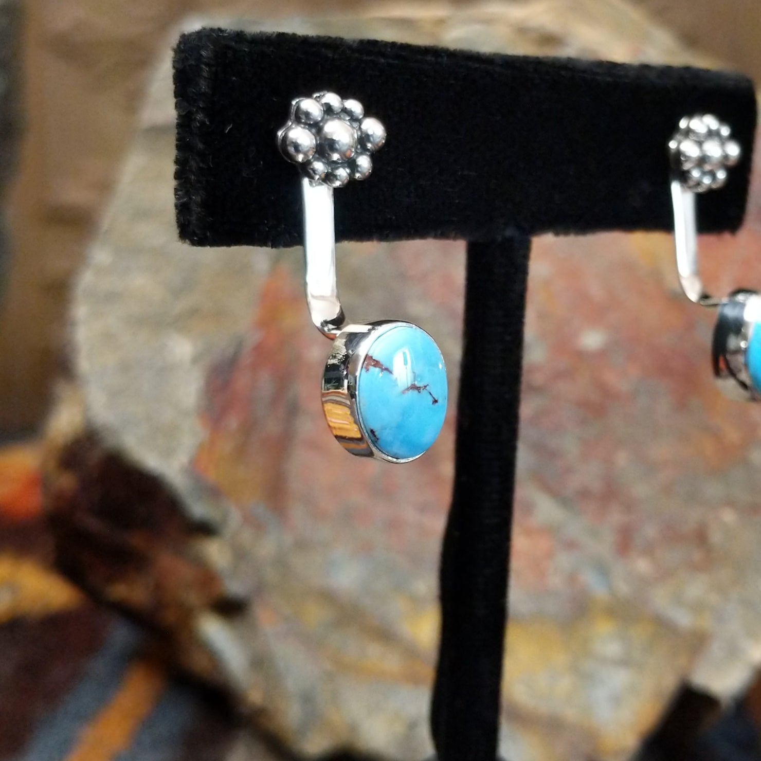 Partial side view of Golden Hills turquoise adjustable earrings displaying a Golden Hills turquoise with light brown matrix veining on a sterling silver band with a plain bezel, crafted by Navajo artist Terry Wood.
