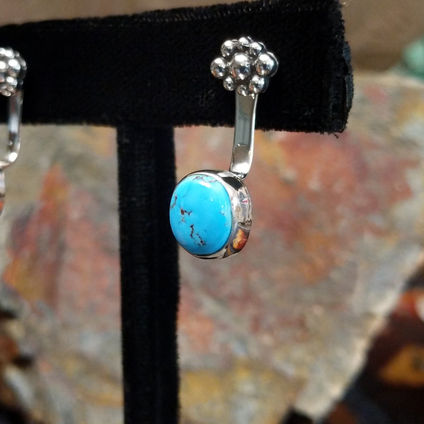 Side view of Golden Hills turquoise adjustable earrings showing a sterling silver band with a plain bezel around a round Golden Hills turquoise with light brown matrix veining, crafted by Navajo artist Terry Wood.