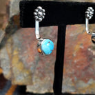 Partial side view of Golden Hills turquoise adjustable earrings displaying a Golden Hills turquoise with light brown matrix veining in a sterling silver frame with a smooth bezel, crafted by Navajo artist Terry Wood.