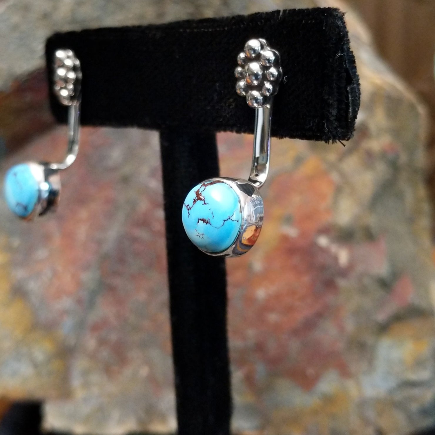 Side view of Golden Hills turquoise adjustable earrings showing a sterling silver frame with a smooth bezel around a round Golden Hills turquoise with light brown matrix veining, crafted by Navajo artist Terry Wood.