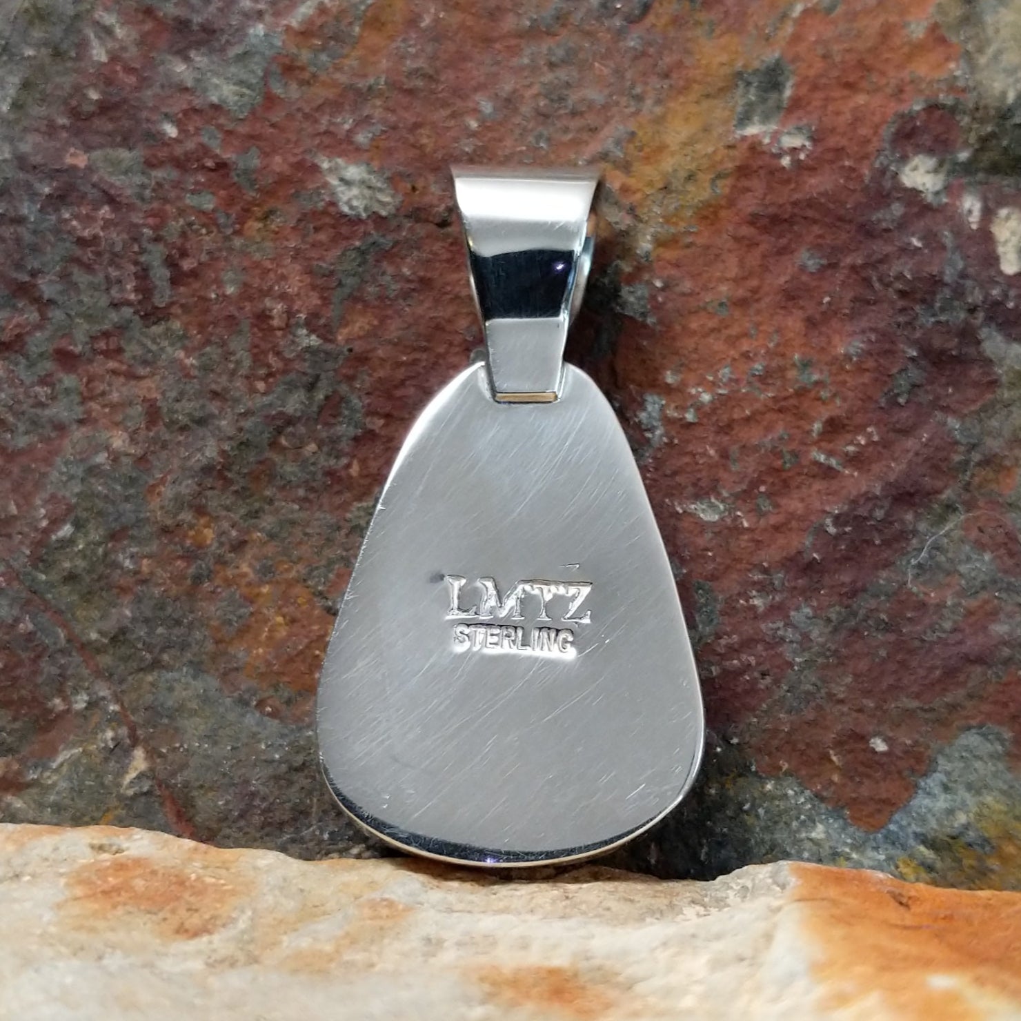 The stamped/signature view shows a small hallmark near the bail, marking Leon Martinez’s artistry, with the turquoise stone’s edge in a simple bezel. 