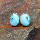The front view of the golden hills turquoise oval earrings by Diane Wylie features vibrant turquoise stones with a brown matrix, set in a simple silver bezel.