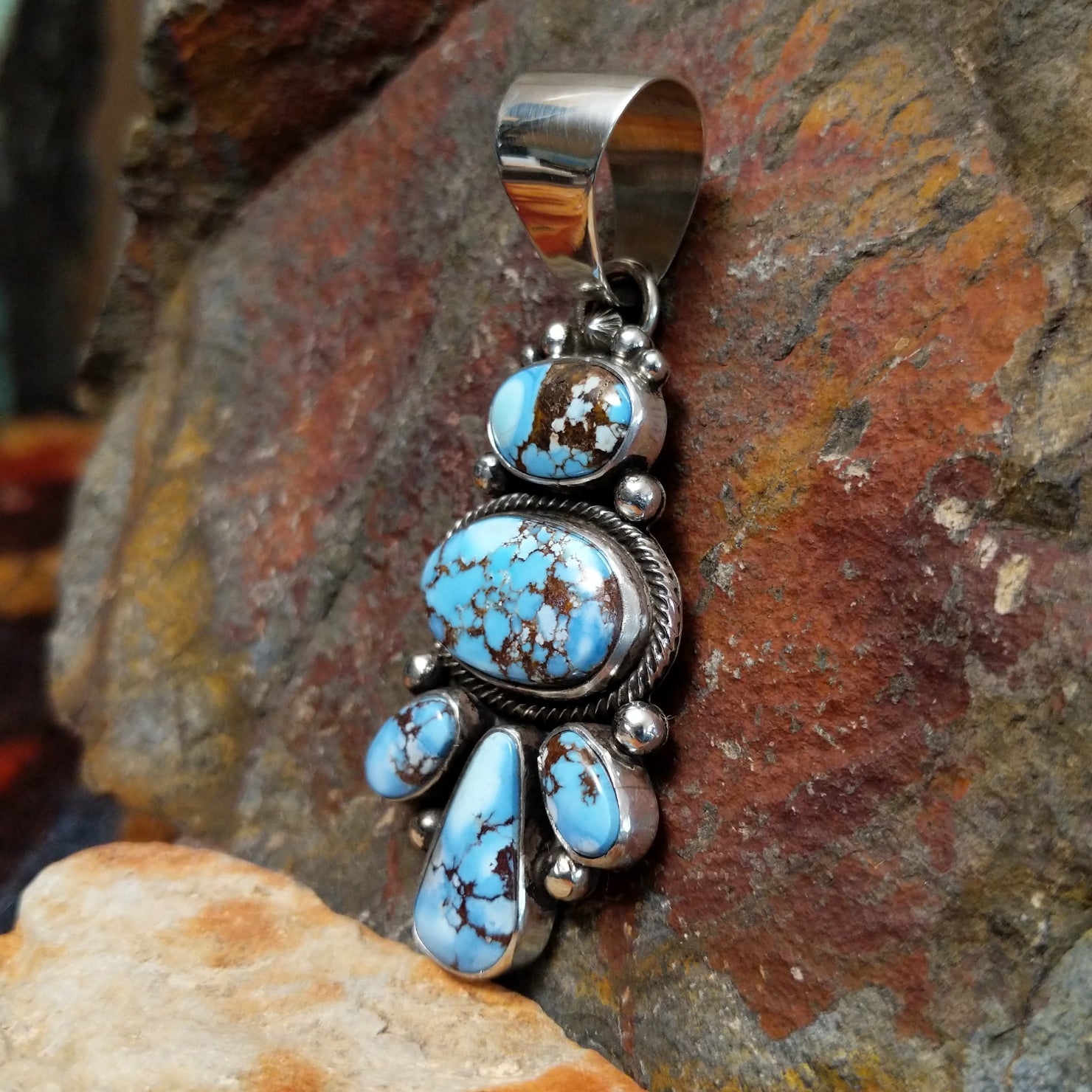 A partial side view showcases the turquoise stones’ matrix patterns in simple bezels, with the twisted rope detail framing the largest stone. Silver beads nestle between, enhancing the Navajo-inspired artistry.