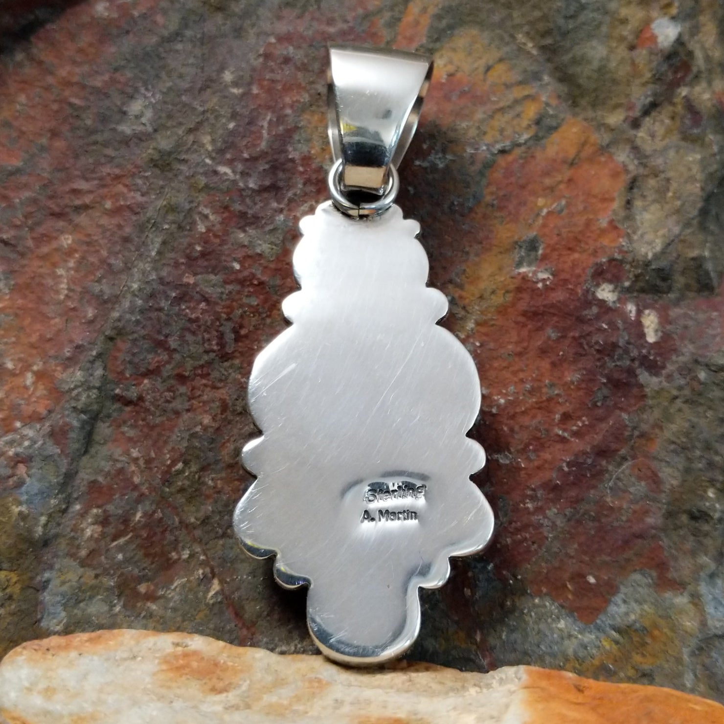 A stamped view near the bail reveals a small hallmark, marking Angela Martin’s artistry on the pendant.
