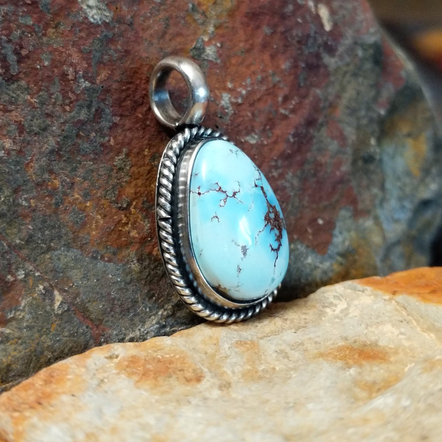  The side of this turquoise pendant shows a sleek silver base with a polished bail at the top.