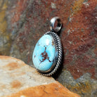 The side of this turquoise pendant shows a sleek silver base with a polished bail at the top.