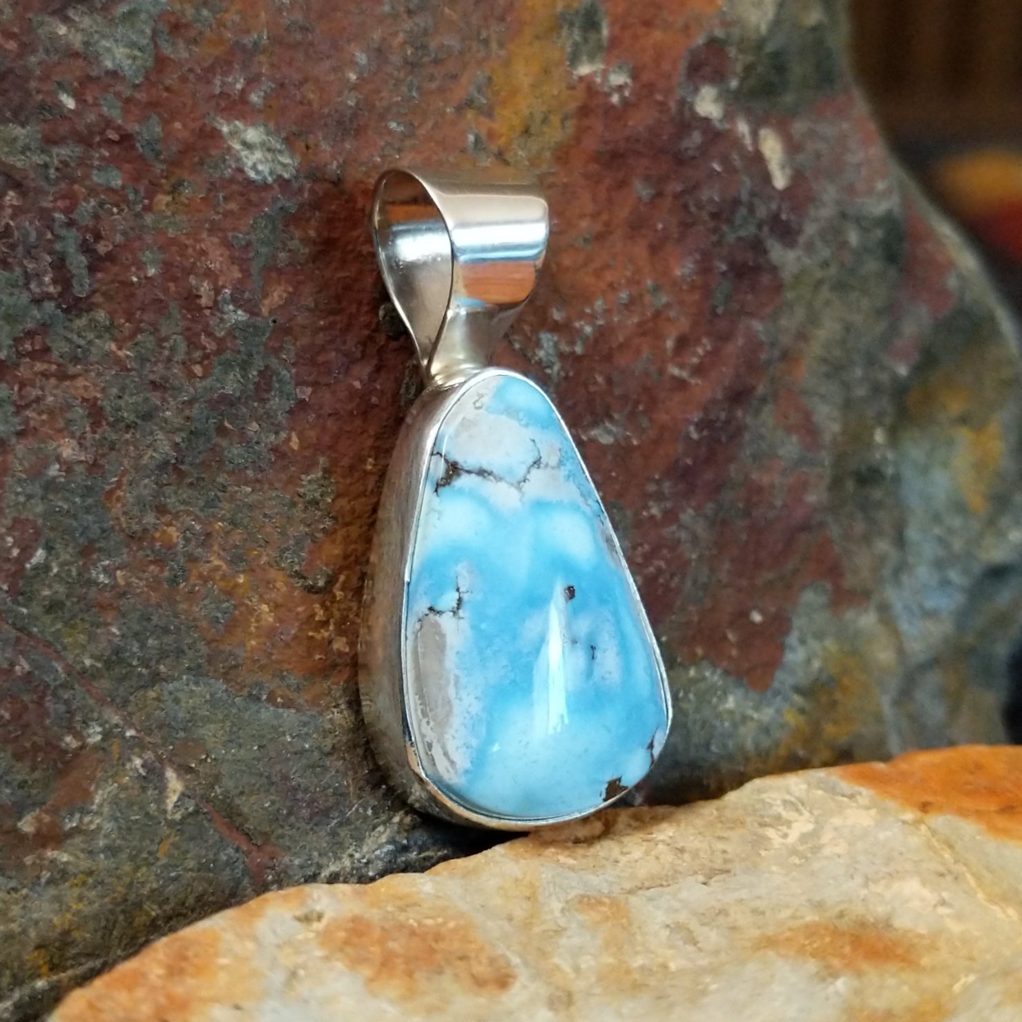 The side of the pendant shows the smooth bezel with the turquoise stone.