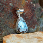 The side of the pendant shows the smooth bezel with the triangular turquoise stone.