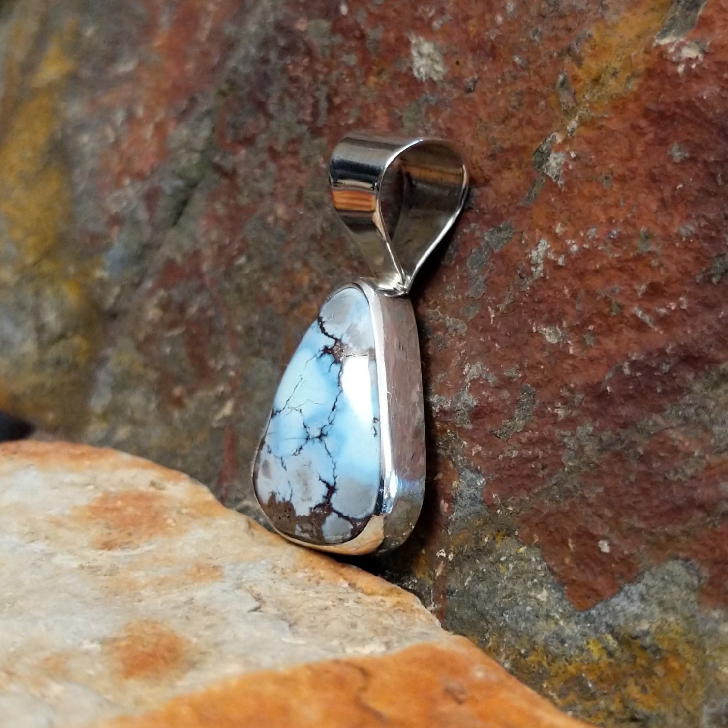 The side of the pendant shows the smooth bezel with the triangular turquoise stone.
