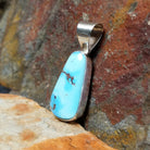 The side of this turquoise pendant reveals a polished silver base with a simple bail at the top.