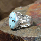 Silver ring with a smooth bezel holding an oval turquoise stone, its twisted silver band.