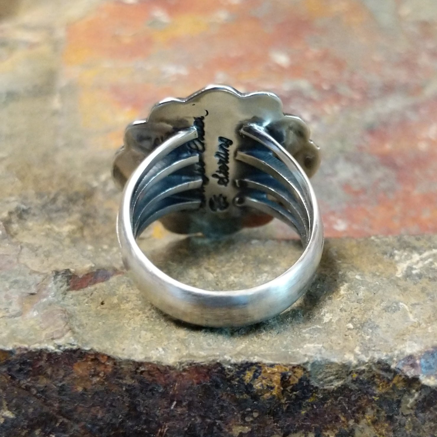 Silver ring with a plain band, no stone visible. Smooth silver finish with scalloped design.