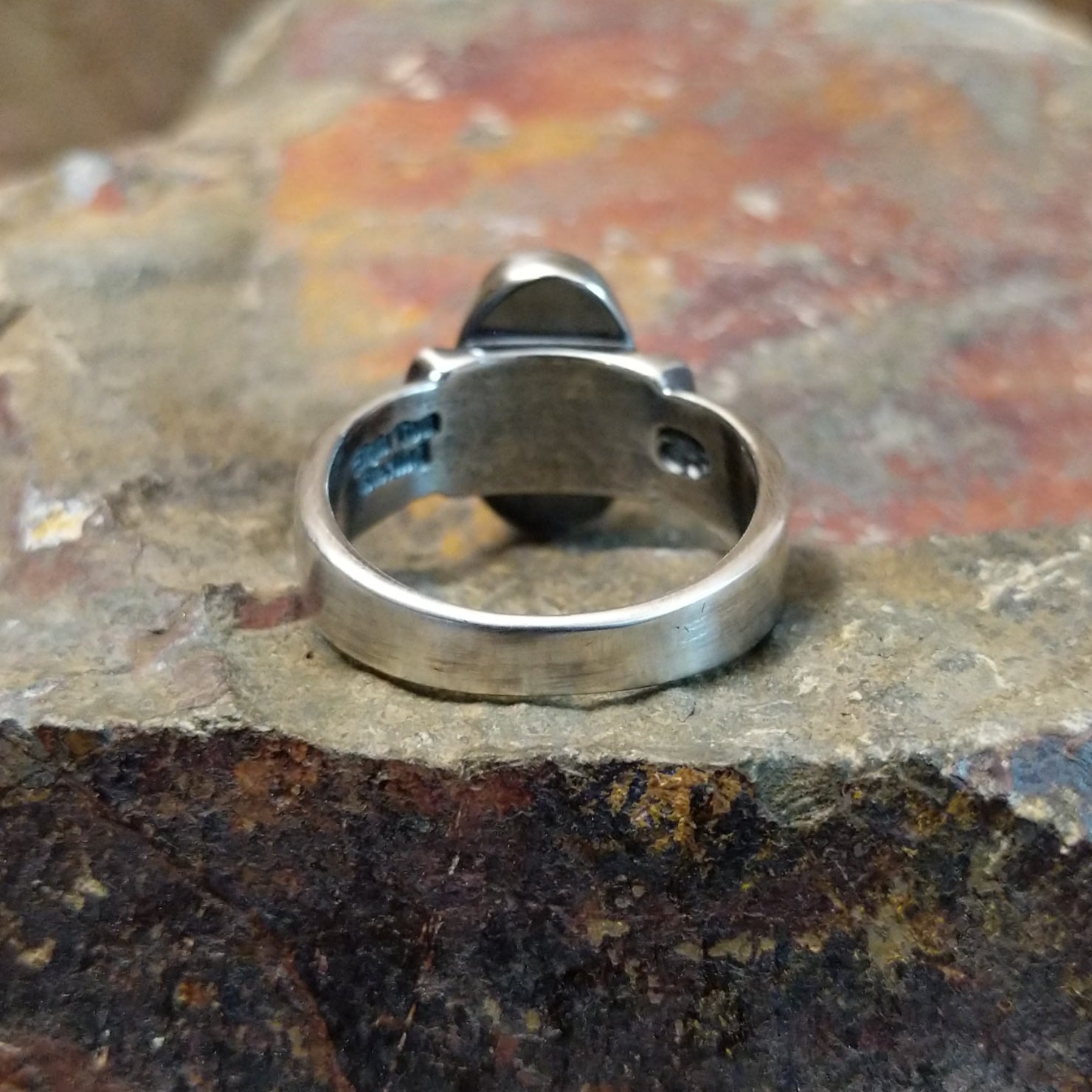 The ring’s polished silver back shows a subtle signature stamp.